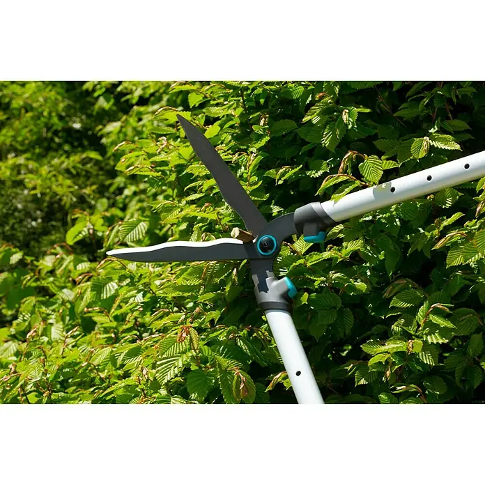 Gardena Hand-Heckenschere TeleCut - Länge: 750 mm, 70 cm - 90 cm - Nahaufnahme einer Gardena Strauchschere, die Äste vor einem grünen Blätterhintergrund schneidet.