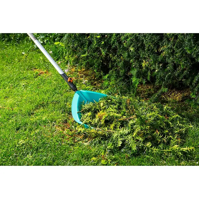 Gardena Combisystem Gartenrechen - Arbeitsbreite: 36,5 cm, 18, Passend für: Gardena Combisystem Stiele - Gartenszene mit einem Laubsammler, der mit abgeschnittenen Ästen gefüllt ist, auf einem grünen Rasen neben einer Hecke.
