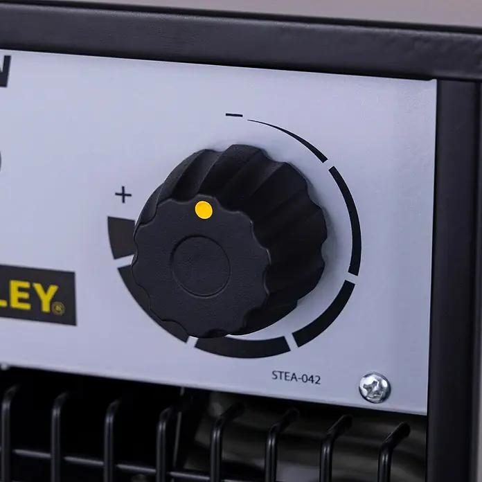 Stanley Heizlüfter SXJH203000E - 3.000 W, 30 m² - Detailaufnahme eines Stanley-Produkts mit Einstellknopf, der auf einer grauen Oberfläche montiert ist.\n