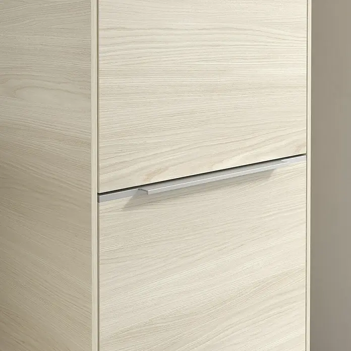 Villeroy & Boch Subway 3.0 Hochschrank - B x T x H: 40 x 36,2 x 171 cm, 2x Tür, White Oak, Farbe Griff: Aluminium glänzend, DIN Anschlag: Rechts - Nahaufnahme eines hellen Holzschranks mit einem horizontalen, silberfarbenen Griff. Der Fokus liegt auf der Textur des Holzes.