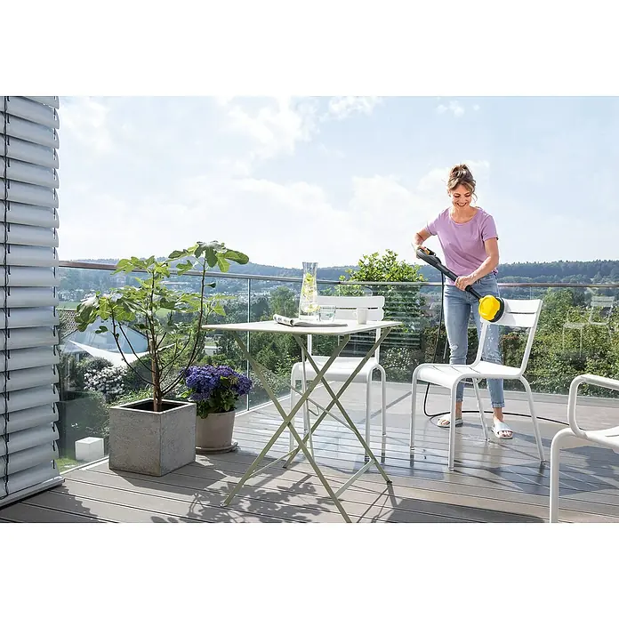 Kärcher Universalreiniger RM 555 - 5 l - Eine Frau reinigt einen weißen Stuhl mit einem gelben Kärcher-Reiniger auf einer Terrasse mit Tisch und Pflanzen.