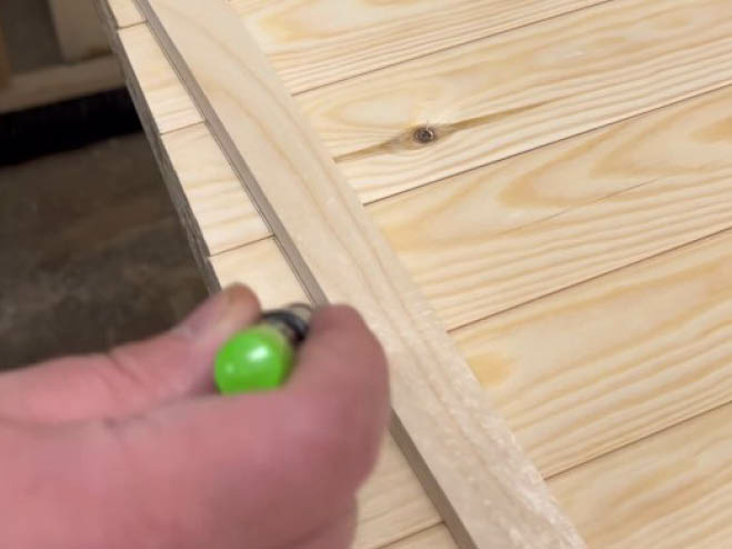 Mit einem Holz als Markierung wird eine Linie auf den Holzlatten mit einem Bleistift gezeichnet