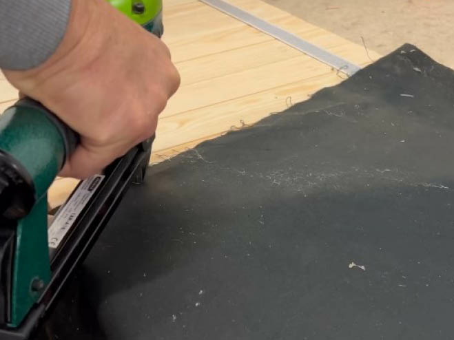 Eine Teichfolie wird auf die Holzlatten getackert