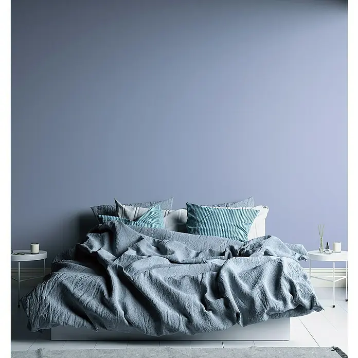 A.S. Création Aquarell Dreams Vliestapete - Blau, Uni, 10,05 x 0,53 m - Elegantes Schlafzimmer mit einem einladenden, zerwühlten Bett mit blaugrauer Bettwäsche, das zum Entspannen einlädt.