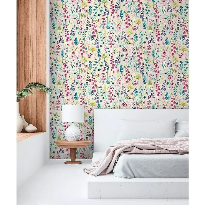 A.S. Création Aquarell Dreams Vliestapete - Weiß-Bunt, Floral, 10,05 x 0,53 m - Nahaufnahme eines Bettes mit Blumendekor an der Wand, das eine lebendige und künstlerische Schlafzimmeratmosphäre erzeugt.