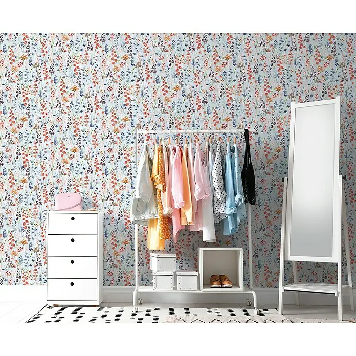A.S. Création Aquarell Dreams Vliestapete - Hellblau-Bunt, Floral, 10,05 x 0,53 m - Ein weißer Kleiderschrank, eine Kleiderstange mit Kleidung und ein Spiegel vor einer floralen Tapete.