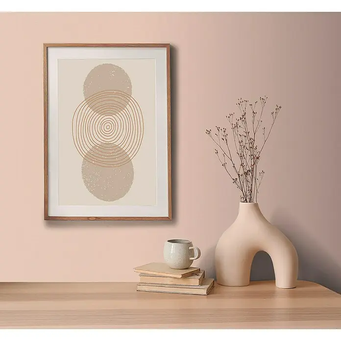 A.S. Création Aquarell Dreams Vliestapete - Apricot-Rosa, Uni, 10,05 x 0,53 m - Ein stilvolles abstraktes Kunstwerk mit Kreismotiven, gerahmt und an einer Wand über einem Tisch mit Deko-Objekten platziert.
