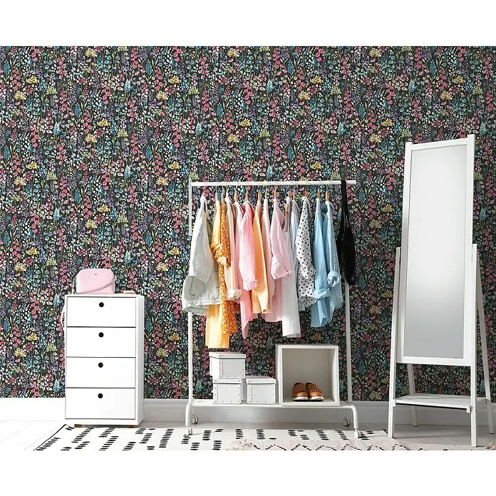 A.S. Création Aquarell Dreams Vliestapete - Schwarz-Bunt, Floral, 10,05 x 0,53 m - Aufnahme eines modischen Zimmers mit Kleiderständer, Spiegel und Kommode vor einer dunklen floralen Tapete.