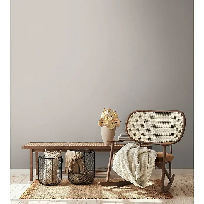 A.S. Création Aquarell Dreams Vliestapete - Braun-Grau, Uni, 10,05 x 0,53 m - Innenaufnahme eines Raumes mit einem Rattansessel, einer Bank, Körben und einer Blumenvase.