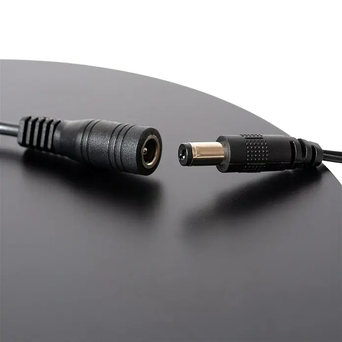 Lucide Zozy LED-Stehleuchte - 4 W, Höhe: 145 cm, Schwarz, Neutralweiß - Ein Bild von zwei unverbundenen, schwarzen DC-Stromkabeln auf einer dunklen Oberfläche. Das Kabel ist ein Standard-Stromkabel.