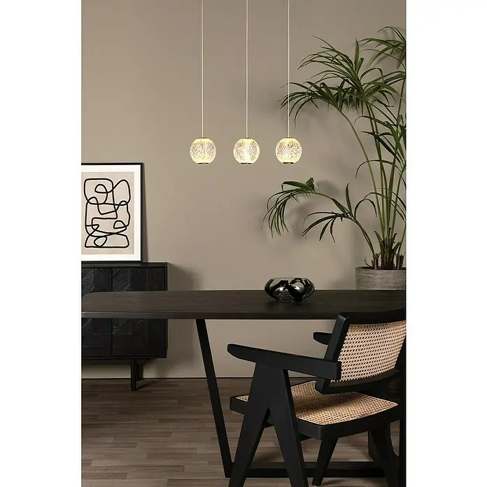 Lucide Cintra LED-Pendelleuchte rund - 4,7 W, L x B x H: 4 x 48 x 150 cm, Kristall, Anzahl Leuchtmittel: 3 Stk. - Innenaufnahme mit drei hängenden Kugel-Pendelleuchten über einem dunklen Esstisch und einem schwarzen Schrank mit Dekorationen.