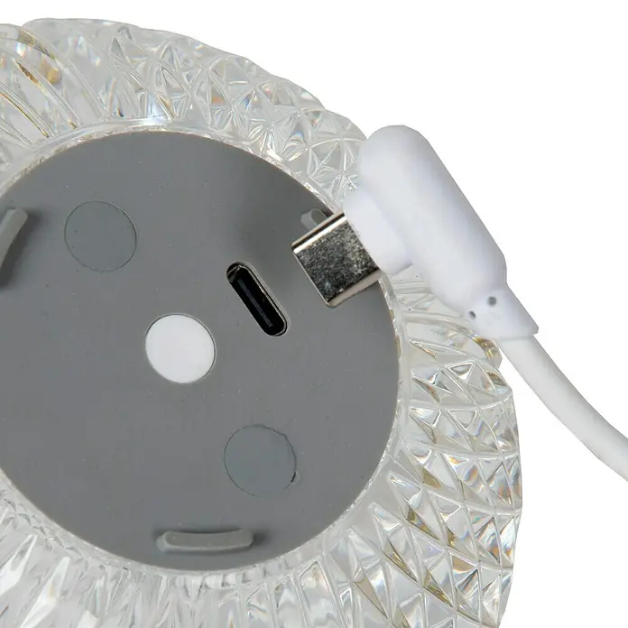 Lucide Cintra Tischleuchte rund - 1,5 W, Ø x H: 9 x 10 cm, Kristall - Nahaufnahme einer Kristalltischlampe mit einem eingesteckten USB-C-Ladekabel, die ihr modernes Design hervorhebt.