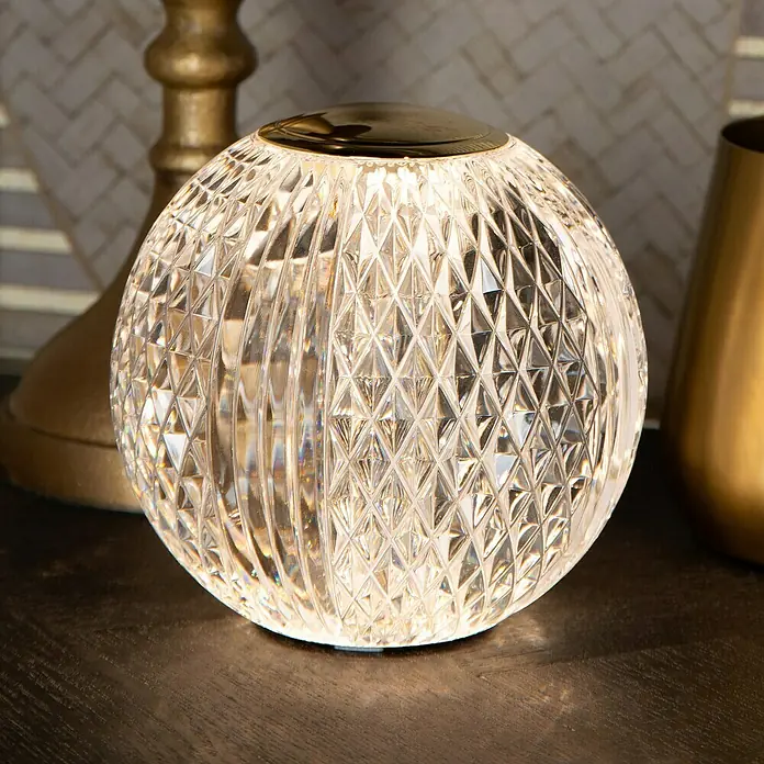 Lucide Cintra Tischleuchte rund - 1,5 W, Ø x H: 9 x 10 cm, Kristall - Nahaufnahme einer funkelnden Kristallkugellampe mit goldenen Akzenten, die ein warmes, einladendes Licht ausstrahlt.