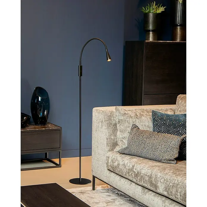 Lucide Zozy LED-Stehleuchte - 4 W, Höhe: 145 cm, Schwarz, Neutralweiß - Elegante Stehlampe neben einem Sofa in einem stilvollen Wohnzimmer. Die Lampe spendet ein angenehmes Licht für gemütliche Stunden.
