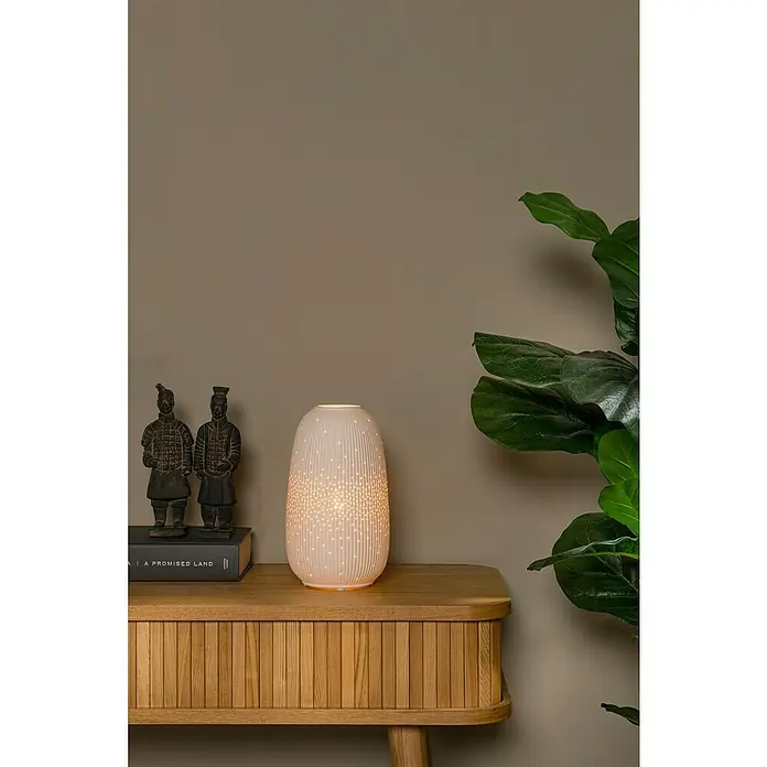 Lucide Deko-Tischleuchte - 25 W, L x B x H: 19 x 14,1 x 24,1 cm, Weiß, E14 - Nahaufnahme einer dekorativen Lampe mit einem sternförmigen Muster, die auf einem Holzschrank steht.