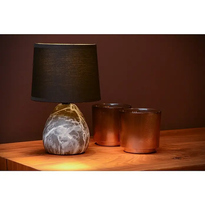 Lucide Deko-Tischleuchte Marmo - 40 W, Schwarz, E14, Ø x H: 16 x 19 cm - Elegante Tischleuchte mit marmoriertem Sockel und schwarzem Schirm neben zwei bronzefarbenen Kerzenhaltern auf einem Holztisch.