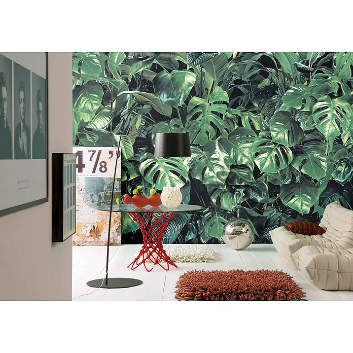 Komar Fototapete Verdure - 8 -tlg., B x H: 368 x 254 cm, Papier - Wohnzimmer mit grüner Blättertapete, rotem Tisch, silberner Kugel und beigem Sofa. Die Blättertapete ist ein Blickfang im Raum.