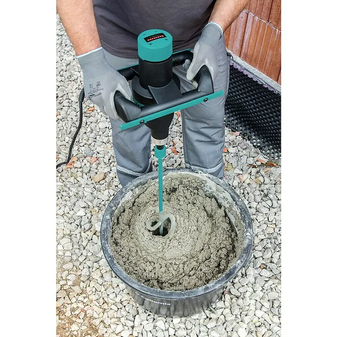 Collomix ErgoMix Rührwerk Ergomix 1400 HF - Mischvolumen: 70 l, Gangzahl: 2 Stk. - Der Collomix CX 20 Handrührwerk mischt Mörtel in einem schwarzen Eimer, der auf einem Kiesbett steht. Die Maschine hat ein grünes Gehäuse und einen schwarzen Motor.