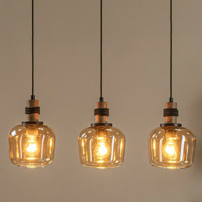Lucide Ilona Pendelleuchte - 40 W, L x B x H: 60 x 8 x 161 cm, Amber, E27 - Nahaufnahme von drei Pendelleuchten mit bernsteinfarbenen Glasschirmen und Holzakzenten, die ein warmes Licht ausstrahlen.