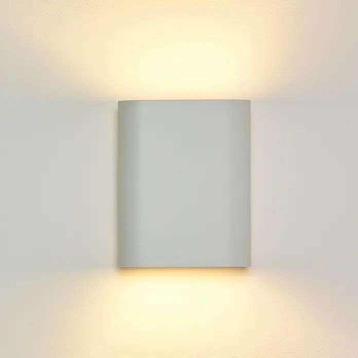 Lucide Wandleuchte Ovalis - 9 W, L x B x H: 18 x 10 x 22 cm, Weiß, E14 - Nahaufnahme einer weißen LED-Wandleuchte, die warmes Licht nach oben und unten abstrahlt und eine moderne Beleuchtung für Innenräume darstellt.