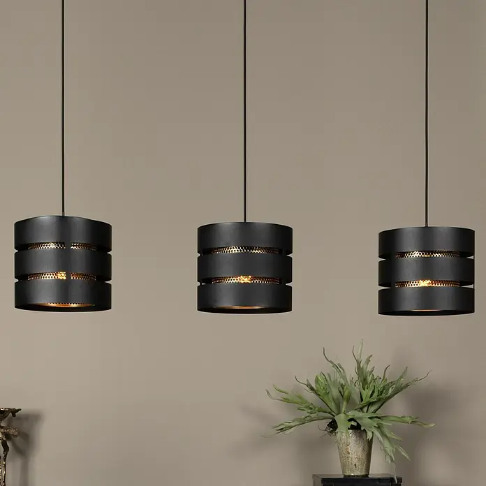 Lucide Rosas Pendelleuchte - 40 W, L x B x H: 110 x 130 x 152 cm, Schwarz, Schwarz/ Gold, E27 - Drei schwarze, zylindrische Hängelampen mit goldenem Gittermuster in einer Reihe über einem Tisch mit einer Pflanze.