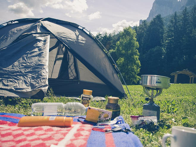 Zelt steht in der Natur mit Picknickdecke, Gaskoscher und Lebensmittel