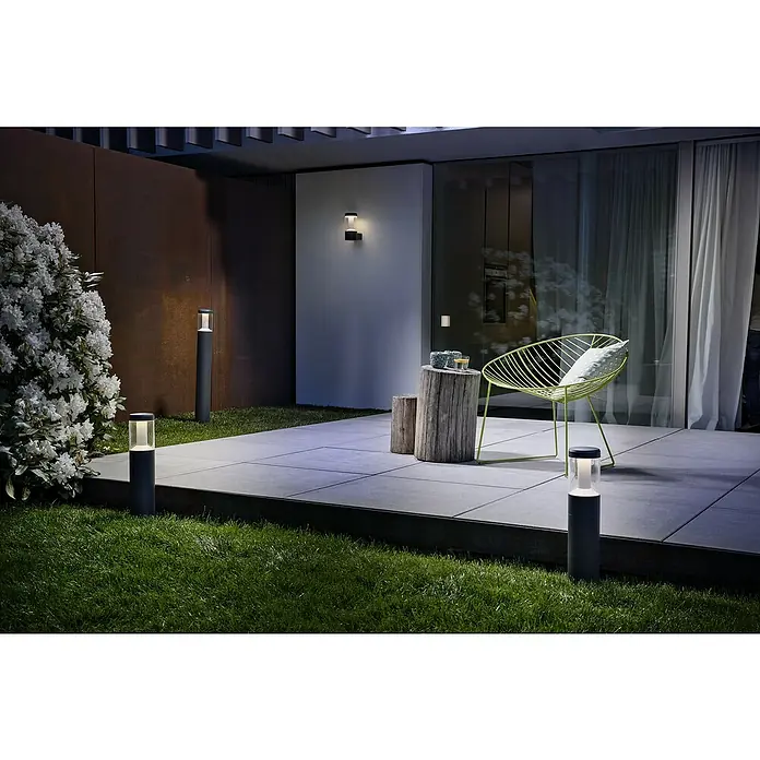 Osram Außensockelleuchte Lantern - Höhe: 90 cm, Warmweiß - Moderne Außenbeleuchtung mit grauen Pollerleuchten auf einer Terrasse mit Stuhl und grüner Bepflanzung.