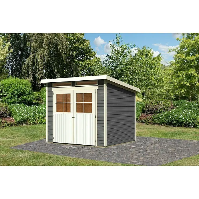 Karibu Gartenhaus Glücksburg - Außenmaß inkl. Dachüberstand (B x T): 267 x 236 cm, Holz, Terragrau, Grundfläche: 5,07 m² - Bild eines grauen Gartenhauses mit weißen Türen und Rahmen, umgeben von Grün. Das Gartenhaus steht auf einem gepflasterten Bereich.