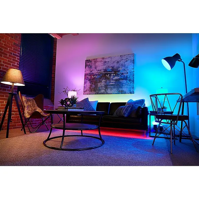 Osram Smart+ Smart-LED-Lampe matter - E27, Dimmbar, RGBW, 1.521 lm, 14 W - Stimmungsvolles Wohnzimmer mit LED-Beleuchtung unter dem Sofa, die eine gemütliche Atmosphäre schafft. Ein modernes Ambiente mit Kunst und stilvollen Möbeln.
