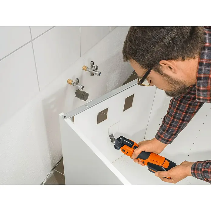 Fein Starlock Hoja de sierra E-Cut Standard - 50 x 35 mm, 3 ud. - Un hombre usa una herramienta multifunción oscilante Fein para recortar secciones en un mueble de baño blanco.