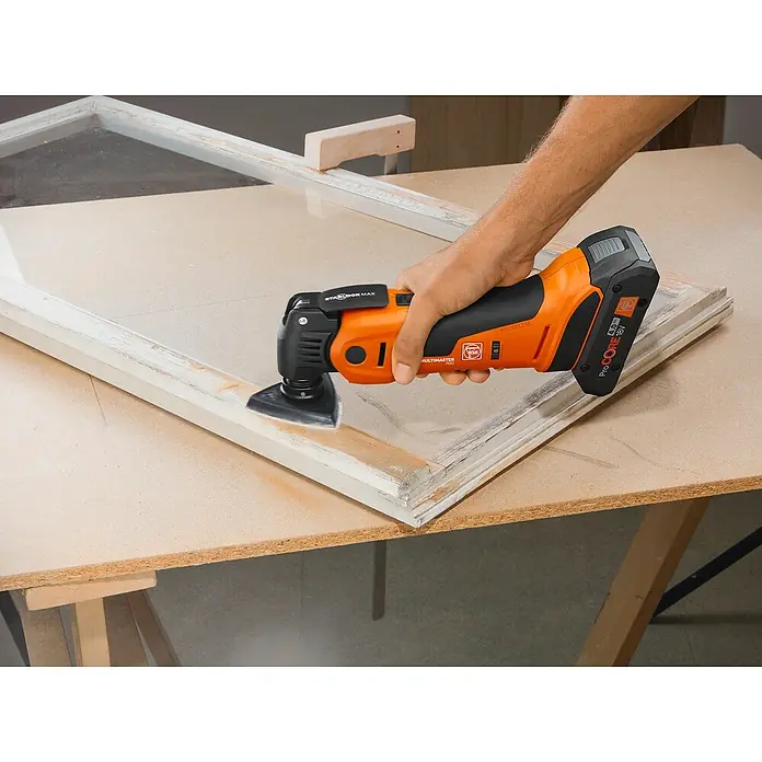 Fein AMPShare 18V Akku-Multifunktionswerkzeug MultiMaster AMM700 MAX AS - 18 V, Ohne Akku, Leerlaufschwingzahl: 10.000 /min - 19.500 /min - Schleifarbeiten mit einem FEIN Multimaster Oszillierwerkzeug an einem Fensterrahmen. Das Gerät ist orange und schwarz.