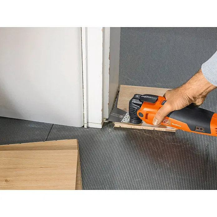 Fein Starlock Plus Hoja de sierra E-Cut Standard - 50 x 65 mm, 1 ud. - La imagen muestra un Fein Multimaster cortando un trozo de madera para encajarlo alrededor de una puerta. Trabajo preciso con Fein Multimaster.