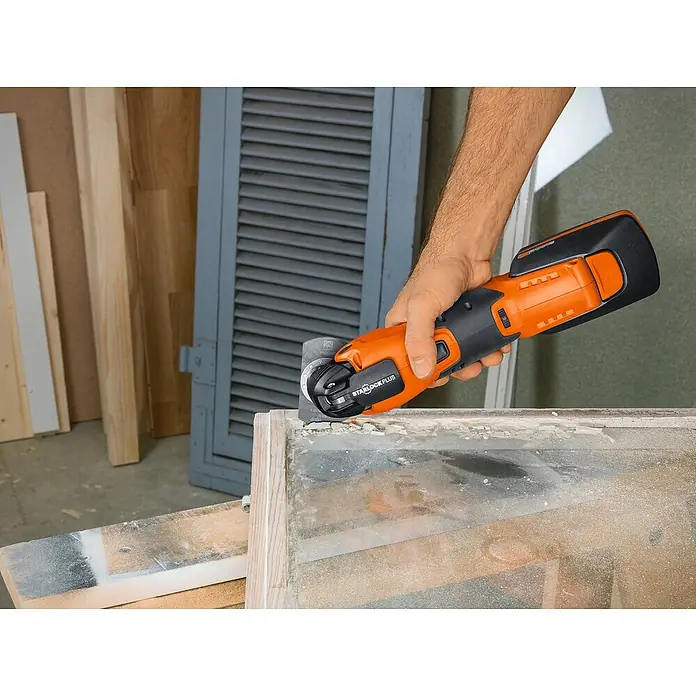 Fein Starlock HSS-Segmentsägeblatt - Durchmesser: 85 mm, HS-Stahl, 1 Stk. - Elektrowerkzeug in Aktion: Ein orangefarbenes Multifunktionswerkzeug von Starlock Plus wird zum Bearbeiten eines Fensterrahmens verwendet.