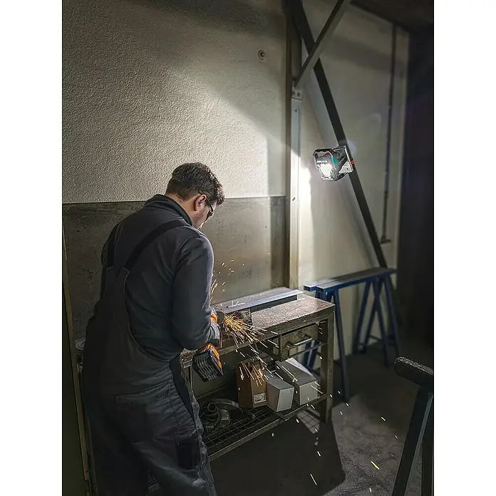 Fein AMPShare 18V Akku-Winkelschleifer CCG 18-125-12 AS - Ohne Akku, Durchmesser Scheibe: 125 mm - Ein Mann arbeitet mit einem Winkelschleifer an einem Metallstück. Funken fliegen, während er das Werkstück bearbeitet.