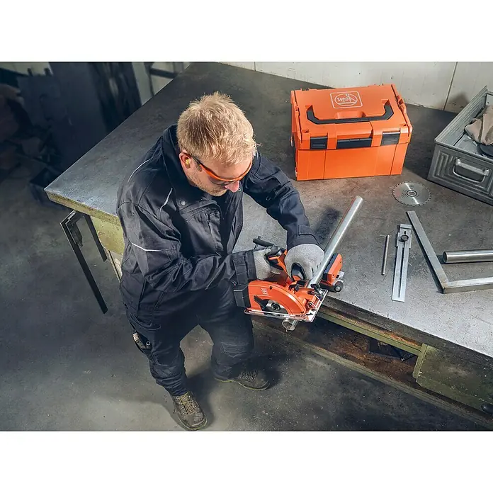 Fein AMPShare 18V Akku-Handkreissäge AHKS 18-57 AS N00 - 18 V, Ohne Akku, Durchmesser Sägeblatt: 150 mm, 1.300 U/min - 2.800 U/min - Ein Handwerker benutzt eine FEIN Metallkreissäge, um ein Metallrohr auf einer Werkbank zu schneiden.