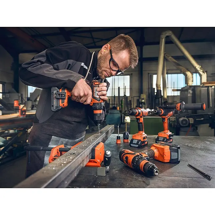 Fein Bohrfutter Q 120 NM - Passend für: FEIN Akku-Schrauber mit QuickIN / QuickIN MAX Schnittstelle - Ein Handwerker bohrt mit einem Akku-Bohrschrauber ein Loch in ein Metallstück, umgeben von weiteren Akku-Werkzeugen.