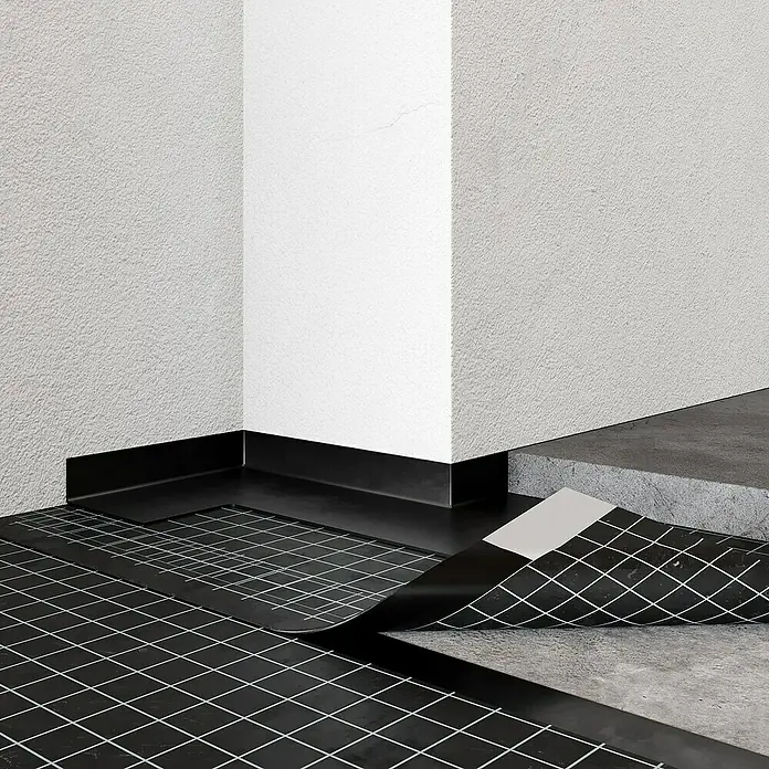 Anschlussstreifen - L x B: 20 m x 20 cm - Produktbild: Schwarze, quadratisch gemusterte Bodenmatte mit Sockelleiste in einem Raum mit strukturierten Wänden.