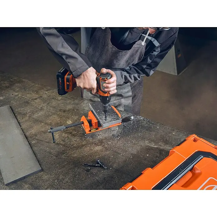 Fein Werkzeughalter - Passend für: 1/2 in Außenvierkant ISO 1174-2 E/F 12.5, 1 Stk. - Eine Bohrmaschine von FEIN bohrt durch ein Metallstück, das in einem Schraubstock eingespannt ist. Werkzeugkiste im Hintergrund.