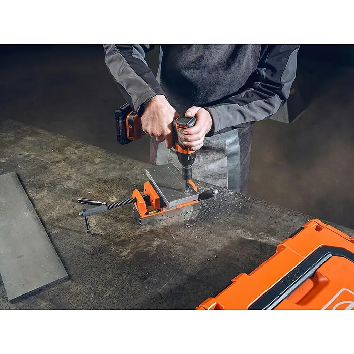 Fein Werkzeughalter - Passend für: 1/2 in Außenvierkant ISO 1174-2 E/F 12.5, 1 Stk. - Ein Handwerker bohrt mit einem Akkubohrer ein Metallstück ein, das in einem Schraubstock fixiert ist. Werkzeugkoffer im Bild.