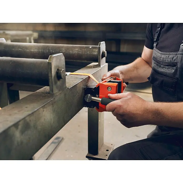 Fein Schraubstock VersaMAG - Spannweite: 108 mm, Metall - Eine orangefarbene Rohrausrichtklemme wird an einem Metallrohr befestigt, um eine präzise Ausrichtung zu gewährleisten. Das Werkzeug optimiert den Montageprozess.