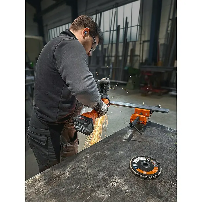 Fein AMPShare 18V Akku-Winkelschleifer CCG 18-125-12 AS - Ohne Akku, Durchmesser Scheibe: 125 mm - Ein Arbeiter benutzt eine Flex zum Schneiden von Metall, Funken fliegen. Im Vordergrund liegt eine Trennscheibe, für präzise Metallarbeiten.