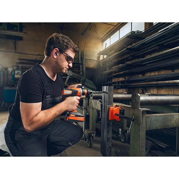 Fein Schraubstock VersaMAG - Spannweite: 108 mm, Metall - Ein Handwerker bohrt mit einer FEIN Akku-Bohrmaschine ein Loch in ein Metallstück, das mit einer Schraubzwinge fixiert ist.