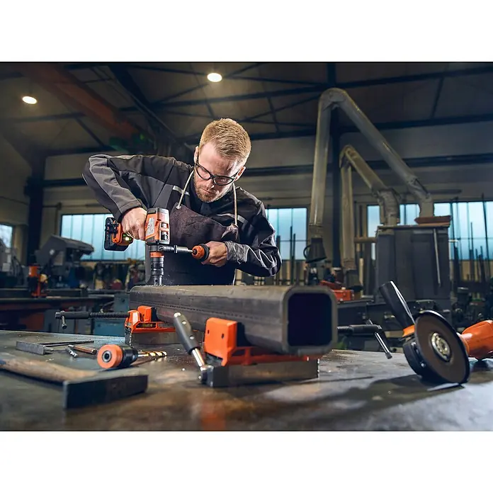 Fein Lochsägen-Adapter - Arbeitsdurchmesser: 0 mm - 40 mm - Ein Handwerker bohrt mit einer orangefarbenen Bohrmaschine ein Loch in ein Metallrohr. Die Bohrmaschine ist das Hauptprodukt im Fokus.