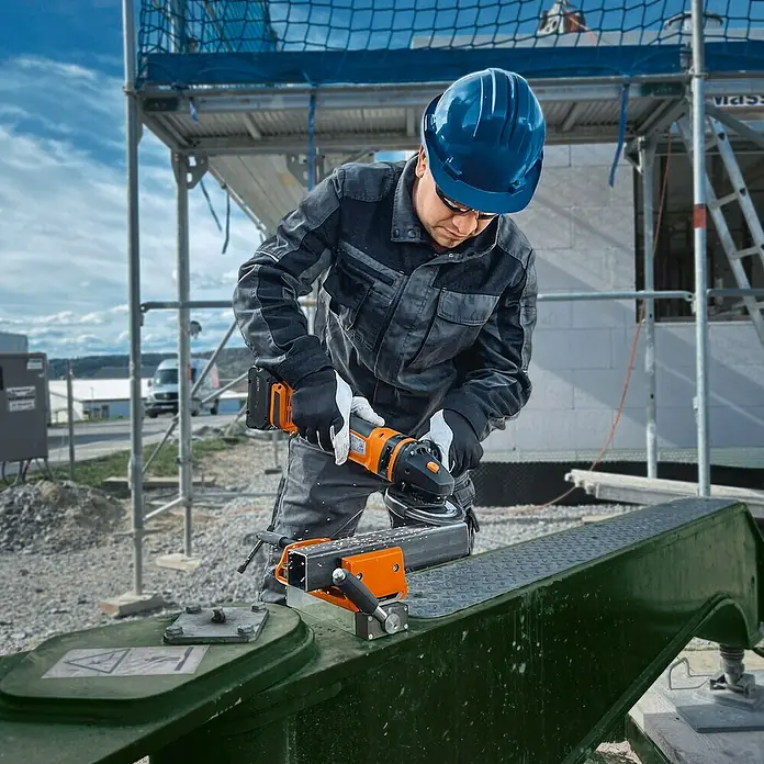 Fein Schraubstock VersaMAG - Spannweite: 108 mm, Metall - Bauarbeiter beim Schleifen von Metall mit einem Akku-Winkelschleifer von Eibenstock auf einer Baustelle.