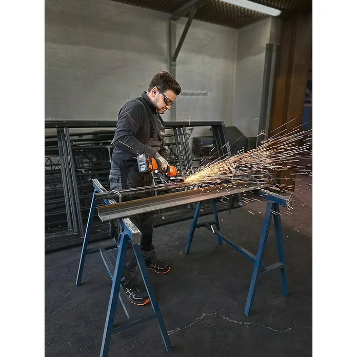 Fein AMPShare 18V Akku-Winkelschleifer CCG 18-125-12 AS - Ohne Akku, Durchmesser Scheibe: 125 mm - Ein Arbeiter benutzt einen Winkelschleifer auf einer Metalloberfläche, wobei Funken fliegen. Er trägt Schutzausrüstung für seine Sicherheit.