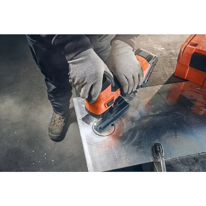 Fein AMPShare 18V Akku-Stichsäge F-IRON Jig 26 AS - 18 V, Leerlaufhubzahl: 700 /min - 3.000 /min - Ein Arbeiter schneidet mit einer FEIN Nibbler Akku-Blechschere ein Loch in ein Metallblech. Das Werkzeug ist orange und schwarz.