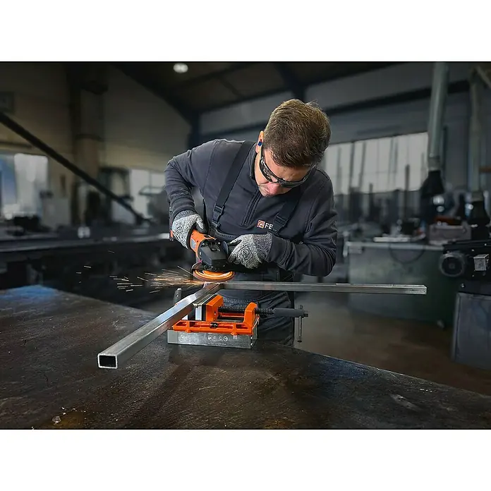 Fein AMPShare 18V Akku-Winkelschleifer CCG 18-125-12 AS - Ohne Akku, Durchmesser Scheibe: 125 mm - Mann mit Schleifmaschine beim Bearbeiten eines Metallstücks in einer Werkstatt. Schutzmaßnahmen werden beachtet.