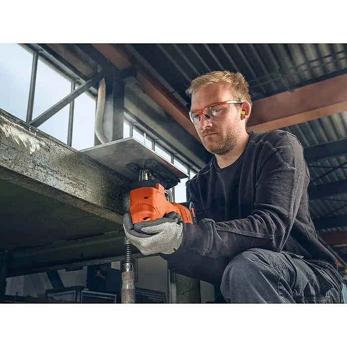 Fein AMPShare 18V Akku-Stichsäge F-IRON Jig 26 AS - 18 V, Leerlaufhubzahl: 700 /min - 3.000 /min - Ein Handwerker benutzt eine orangefarbene Stichsäge mit Akku, um ein Metallstück zu schneiden. Sicherheitsausrüstung ist vorhanden.