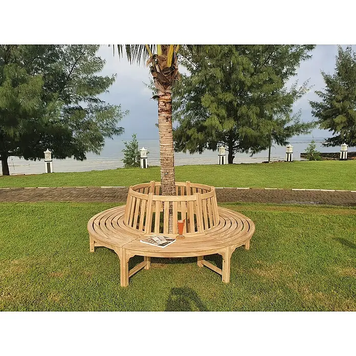 Joda Baumbank 360° - Ø x H: 220 x 90 cm, Teak, Naturbraun - Eine runde Holzbank umgibt einen Baum im Freien, ideal für einen entspannten Aufenthalt mit Buch und Getränk.