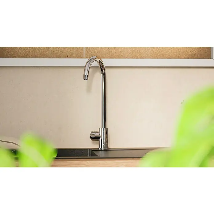 Grohe Spültischarmatur Blue Home Mono - Höhe: 37,9 cm, C-Auslauf, Chrom, Glänzend, Schwenkbar - Eine elegante, verchromte Küchenarmatur vor einem neutralen Hintergrund, teilweise von Pflanzen verdeckt.